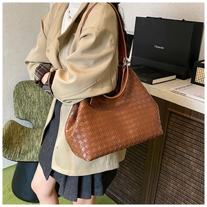 Detailed close-up of the woven leather texture on a large brown tote bag for daily commute