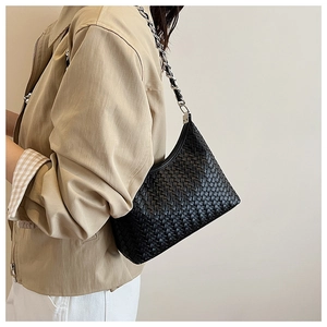 Close-up of black woven leather shoulder bag with a stylish metal chain strap detail