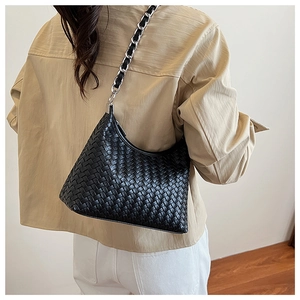 Detail showing black woven leather hobo bag with silver chain strap on model shoulder
