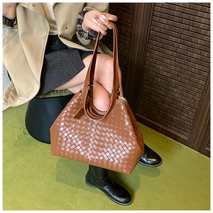 Brown woven tote bag with dual shoulder straps shown in a minimalist lifestyle setting