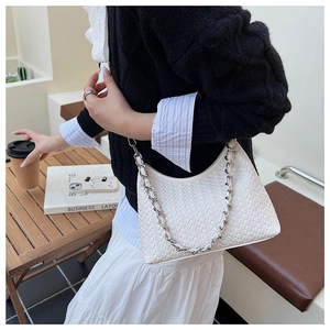 Detail of white woven hobo bag with chunky silver chain on a cafe table setting