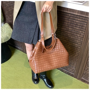 Detailed close-up of a woven brown tote bag featuring premium PU leather and cross-weave texture