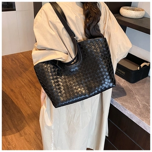 Detail of black woven leather tote bag with checkerboard pattern on female model back