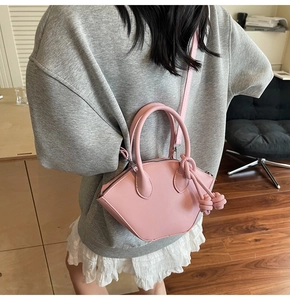 Pink shell bag with knotted tassel detail shown in a stylish indoor lifestyle scene