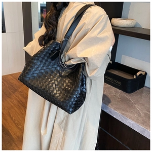 Lifestyle view of black woven leather tote bag shown on a shoulder for daily commute