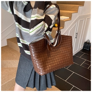 Detailed view of large brown woven leather tote bag with shoulder strap and handle