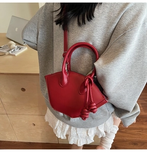 Red leather handbag for women styled with a white pleated skirt in a lifestyle setting