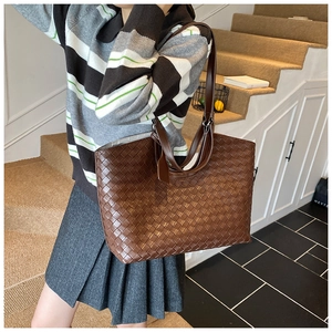 Detailed view of the dark brown woven leather texture and sturdy strap on this tote bag