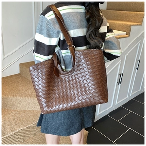 Detailed view of the dark brown hand-woven leather texture on this large tote bag