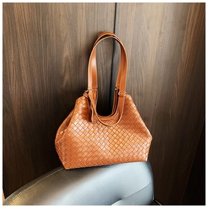 Detail of the brown woven tote bag featuring high-quality Intrecciato craft on a leather seat