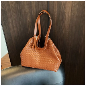 Detail of brown woven tote bag showing luxury leather weave texture and durable handles
