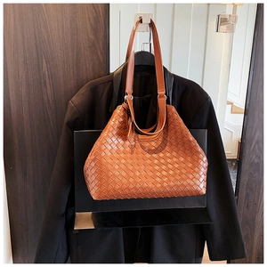 Detail of woven brown leather tote bag with elegant texture and long shoulder straps