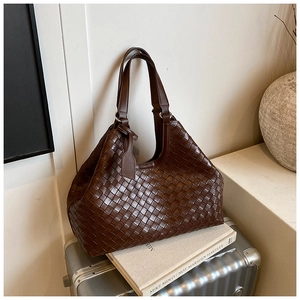 Close-up of a large coffee brown woven tote bag featuring classic leather weaving texture