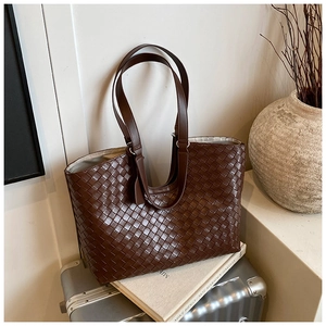 Macro view of detailed dark brown woven leather texture and handles on the tote bag