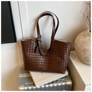 Close-up of dark brown woven leather texture and handles on the large tote bag