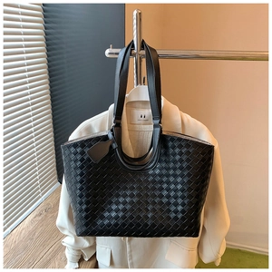 Detail of woven black tote bag featuring classic Intrecciato craftsmanship on a white suit