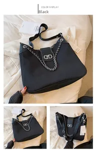 Detail of black canvas tote bag showing silver chain, geometric lock, and leather trim