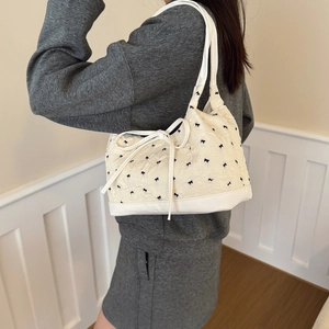 White ribbon bow hobo bag with textured fabric and leather strap shown on shoulder
