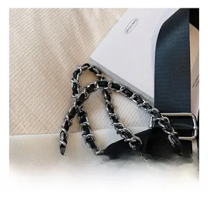 Detail of black nylon shoulder strap with silver buckle and braided chain strap