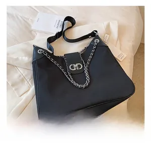 Detailed close-up of black crossbody bag with silver chain and metal buckle closure