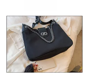 Detail of black tote bag with silver CD buckle, metal chain and smartphone for size reference