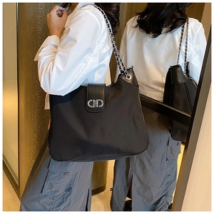 Detail of black nylon and leather tote bag with silver chain and metal buckle logo