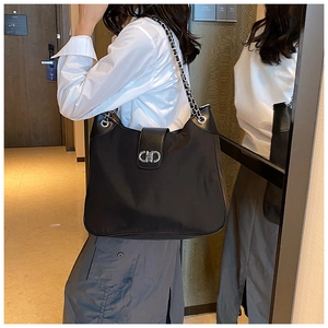 Detail of black soft leather tote bag with silver chain strap and metal clasp closure