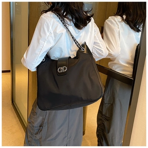 Macro view of black soft leather tote bag with silver chain strap and metal lock closure