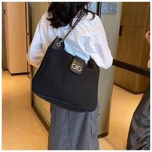 Detail of black tote bag with silver chain strap and metal clasp in a stylish setting