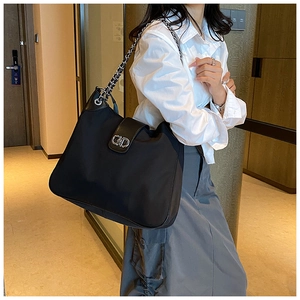 Detail of black nylon hobo bag with silver chain strap and metal ring lock closure