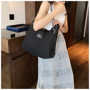 Detail of black nylon tote bag featuring silver chain strap and interlocking buckle