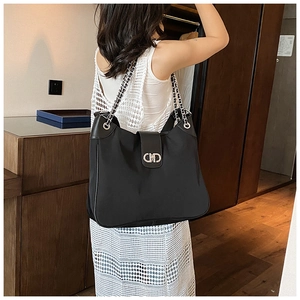 Detail of black soft leather hobo bag with silver chain strap and CD metal clasp on model
