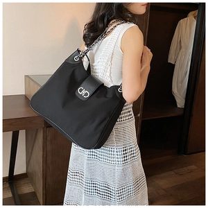 Detail of black tote bag with silver CD buckle and metal chain strap in elegant style