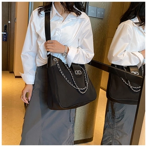 Detail of large black tote bag with silver chain decor and premium nylon leather mix