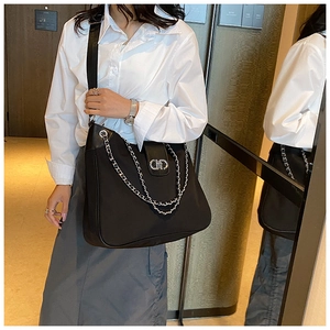 Detail of black nylon tote bag featuring silver chain decoration and metal magnetic closure