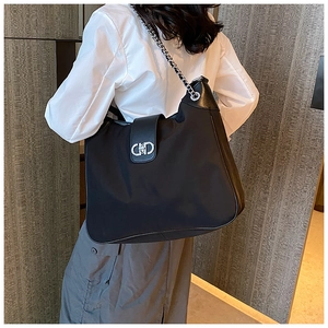 Close-up of black shoulder bag with silver chain strap and circular metal buckle detail