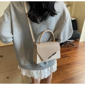 Detail of beige sequin flap bag showing glossy texture and silver metal trim accents
