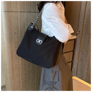 Detailed view of silver CD logo buckle and chain strap on black soft leather tote bag