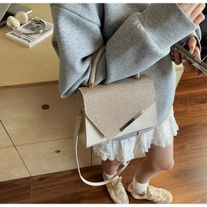 Close-up of beige handbag featuring sparkling sequins and elegant gold metal trim