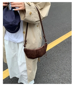 Sac croissant en daim marron foncé de style français présenté en contexte urbain
