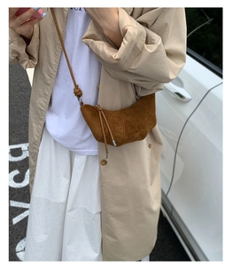 Détail d'un sac croissant en daim marron montrant sa forme en croissant et sa bandoulière nouée