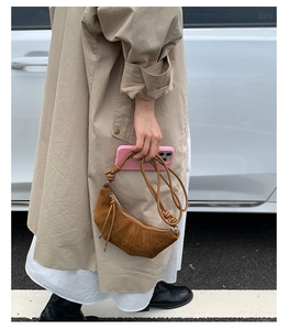 Photo de rue d'un sac croissant en daim marron avec détail de bandoulière nouée chic