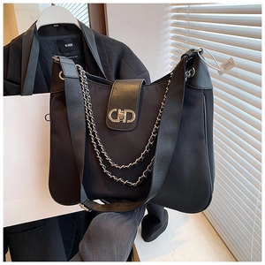 Detail of black tote bag featuring metallic twist lock and decorative chain strap