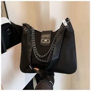 Macro view of black tote bag with gold CHD lock detail and decorative metal chain