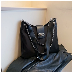 Detail view of the silver CD logo buckle and chain on the black leather tote bag