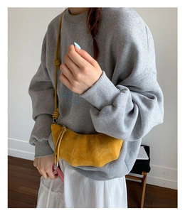 Détail du sac croissant jaune gingembre montrant la texture suédée et le design plissé