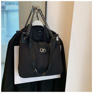 Detail of black nylon shoulder bag with chain strap and round metal buckle on suit