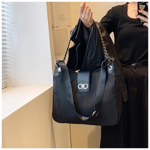 Detail of metal chain and double D buckle on black nylon tote bag with wide strap