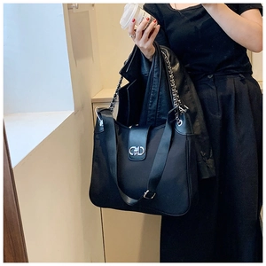 Close-up of black shoulder bag featuring CD metal buckle and dual strap details