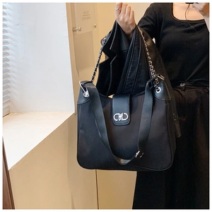 Detail of black tote bag with silver metal chain strap and logo lettering clasp